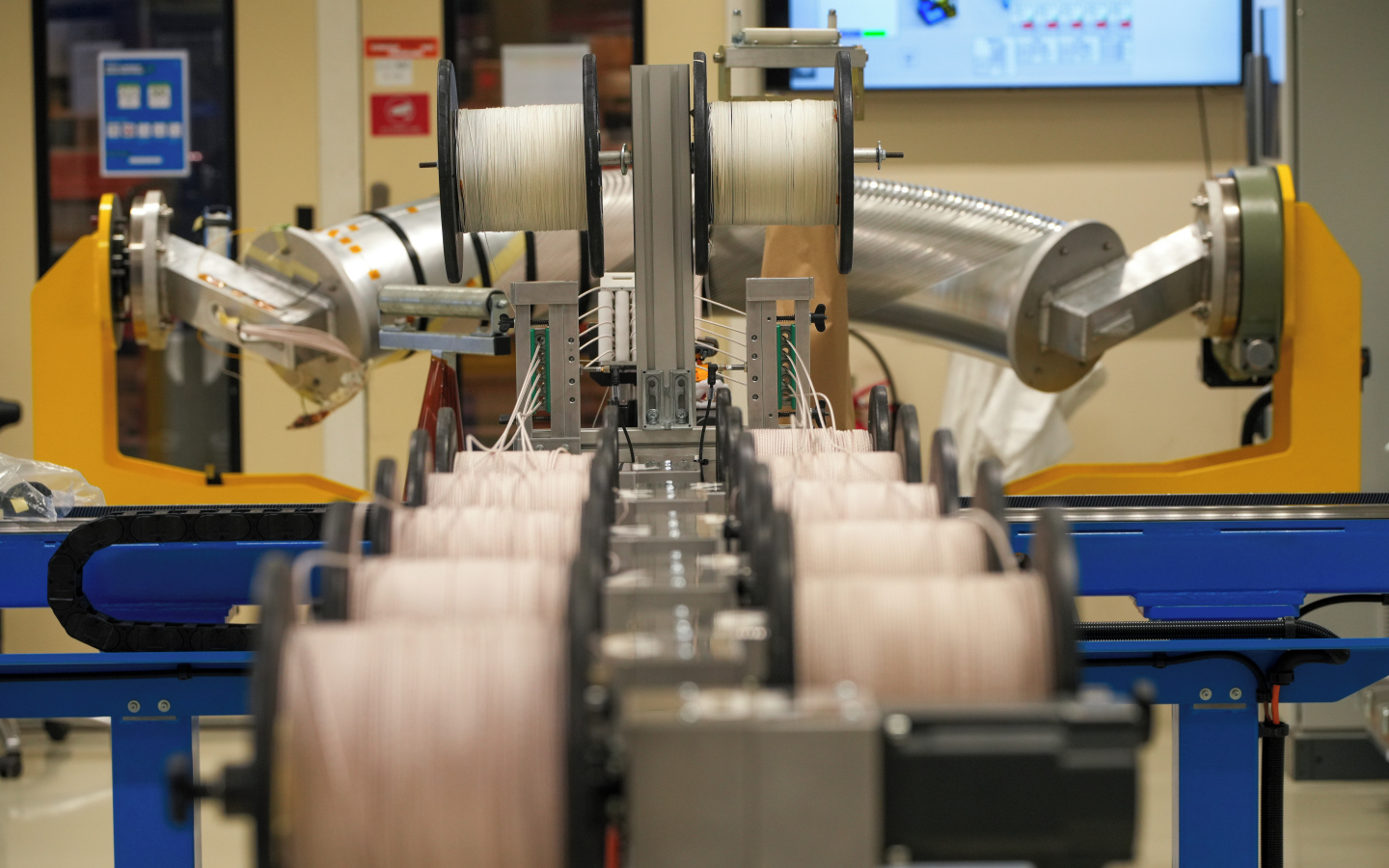 A close-up view of the cable manufacturing process, where multiple spools feed insulated wires through a guide that stacks the cables evenly for the next production step